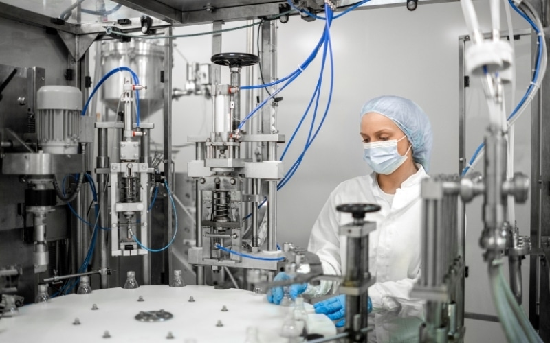 A worker operates a liquid container filling machine.