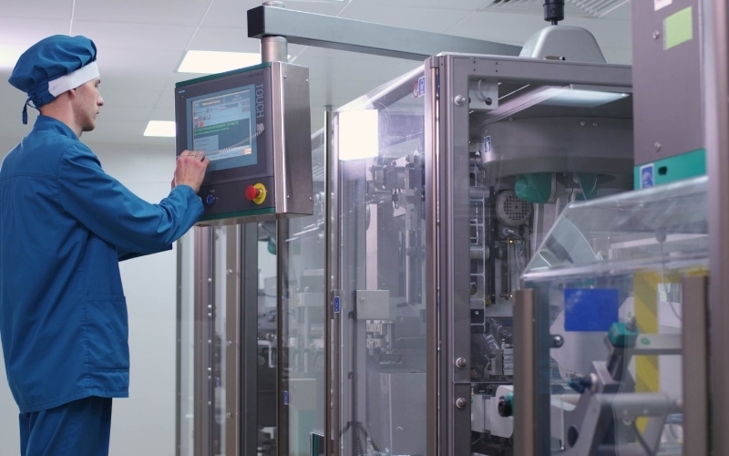A worker operates a product manufacturing machine for food products.