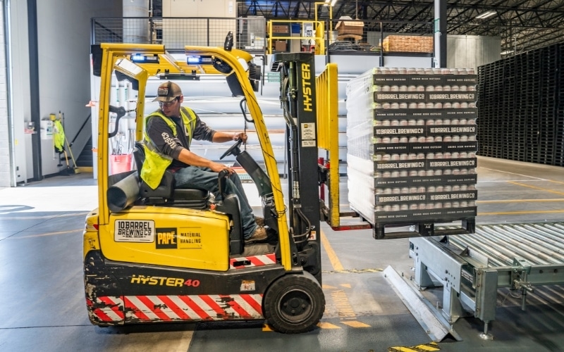 A worker drives a forklift in a contract packaging facility.