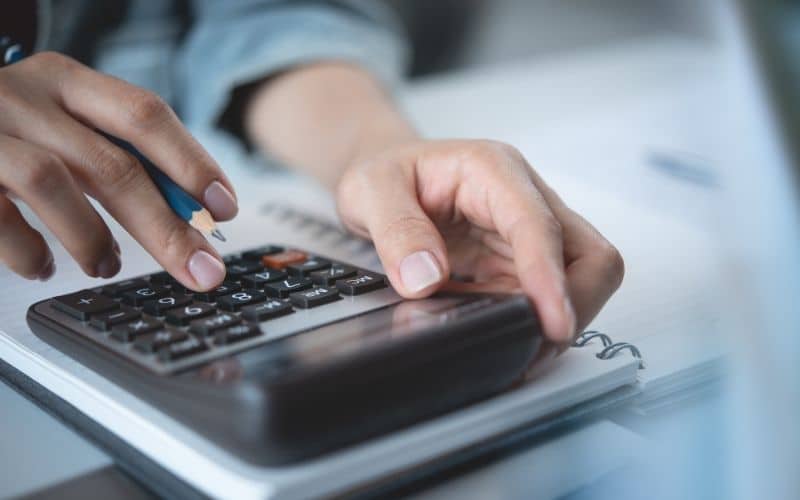 A person taps into a calculator to estimate cost savings for a contract manufacturing partnership.