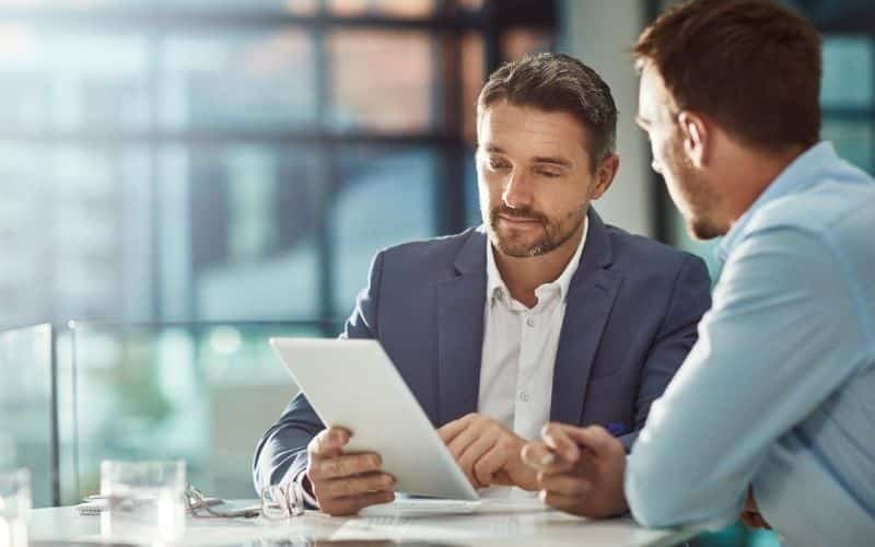 A businessperson holds a tablet, interviewing a contract manufacturer.