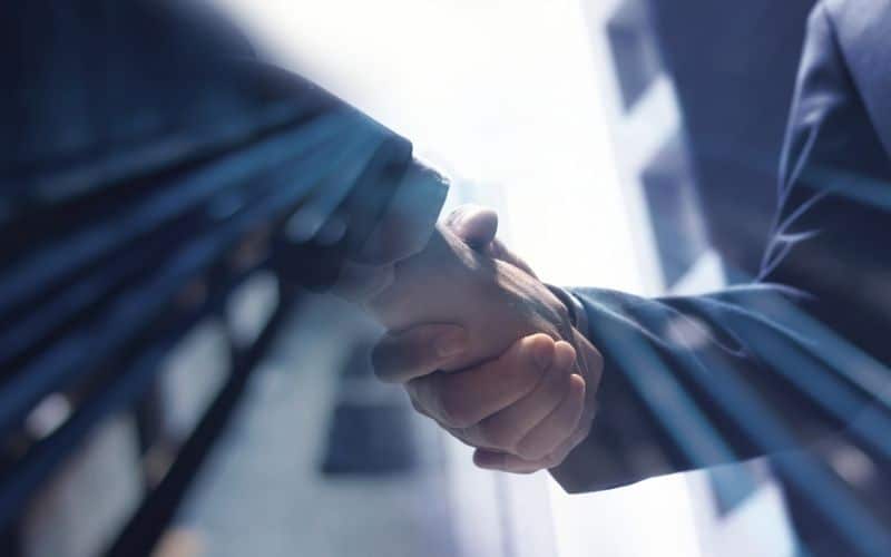 A business owner and a contract manufacturer shake hands.