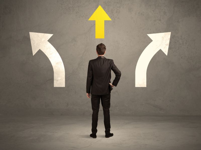 A man in a suit faces three paths, represented by arrows.