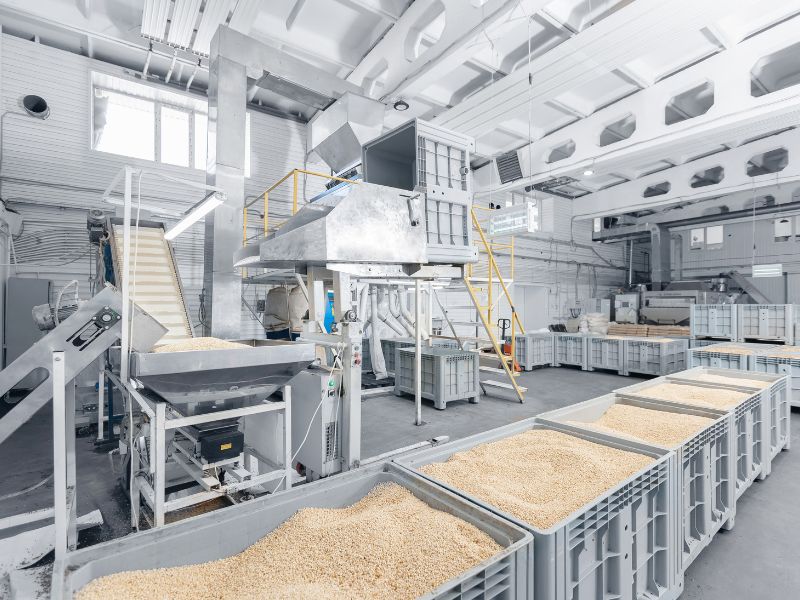 A granular food mix is held in large, square containers at a packaging facility