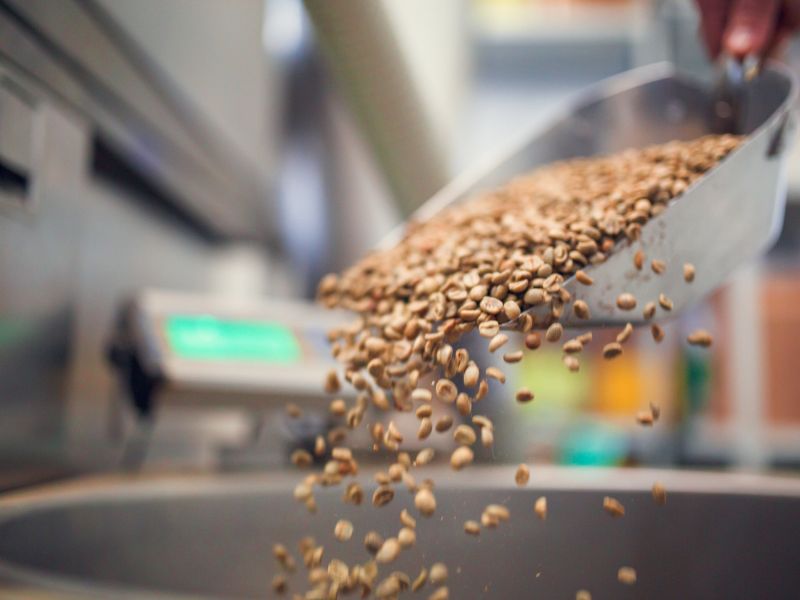 Grains are spilling out of a scoop at a food packaging facility.